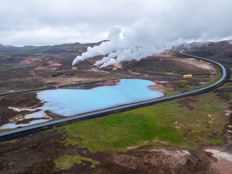 Aerial view of the Hverir geothermal area featuring steam vents a vibrant blue geothermal pool and a winding road in Reykjahlid Thingeyjarsveit Iceland. Aerial view of the Hverir geothermal area featuring steam vents a vibrant blue geothermal pool and a winding road in Reykjahlid Thingeyjarsveit Iceland.