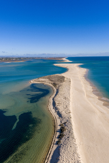 Aerial view of the sandbar and turquoise waters of Praia da Fuseta with dunes and the Atlantic Ocean under a clear blue sky in Fuseta Faro District Portugal. Aerial view of the sandbar and turquoise waters of Praia da Fuseta with dunes and the Atlantic Ocean under a clear blue sky in Fuseta Faro District Portugal.