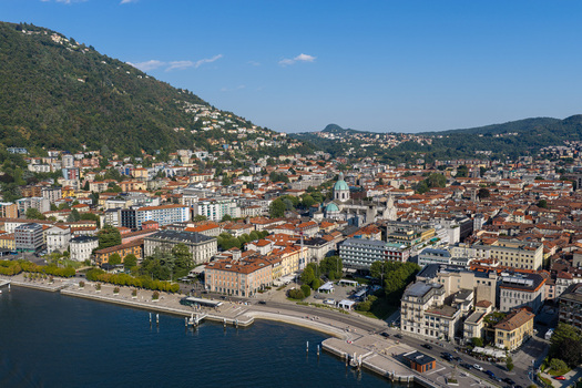 Aerial view of the historic city of Como featuring the cathedral dense urban rooftops and the waterfront along Lake Como in Como Lombardy Italy.