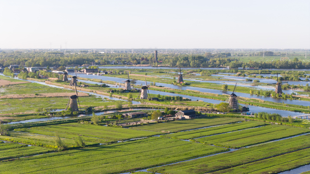 Aerial view of the historic Kinderdijk windmills standing along canals in the lush green polder landscape under a clear sky Kinderdijk South Holland Netherlands. Aerial view of the historic Kinderdijk windmills standing along canals in the lush green polder landscape under a clear sky Kinderdijk South Holland Netherlands.