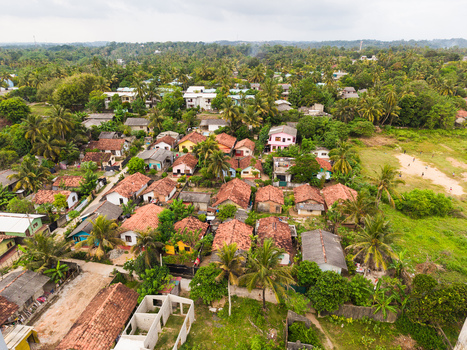 Aerial view of traditional houses with tiled roofs nestled among lush palm trees and tropical vegetation under an overcast sky in Galle Southern Province Sri Lanka. Aerial view of traditional houses with tiled roofs nestled among lush palm trees and tropical vegetation under an overcast sky in Galle Southern Province Sri Lanka.