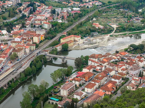 Aerial view of the town of Leccio with its red roofed buildings a stone bridge crossing the river and a railway line running alongside the urban area in Leccio Toscana Italy. Aerial view of the town of Leccio with its red roofed buildings a stone bridge crossing the river and a railway line running alongside the urban area in Leccio Toscana Italy.