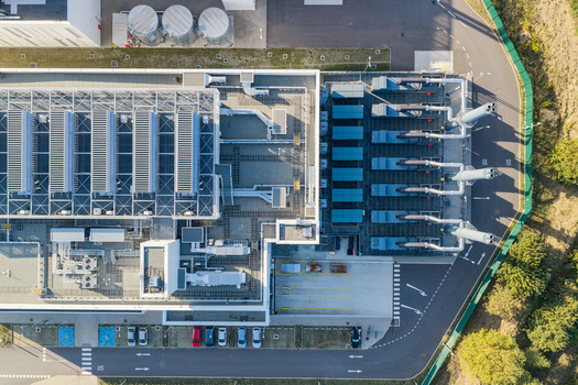 Aerial view of Vantage Data Centers BER1 facility featuring rooftop cooling units industrial infrastructure and parking area in Ludwigsfelde Brandenburg Germany. Aerial view of Vantage Data Centers BER1 facility featuring rooftop cooling units industrial infrastructure and parking area in Ludwigsfelde Brandenburg Germany.