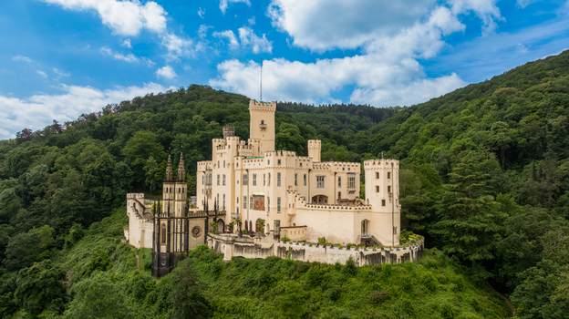 Aerial view of Stolzenfels Castle nestled on a lush green hillside surrounded by dense forest under a bright blue sky with scattered clouds Koblenz Rheinland Pfalz Germany. Aerial view of Stolzenfels Castle nestled on a lush green hillside surrounded by dense forest under a bright blue sky with scattered clouds Koblenz Rheinland Pfalz Germany.