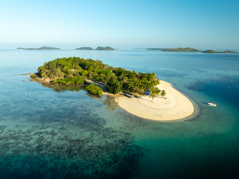 Aerial view of Pass Island featuring lush tropical vegetation a pristine white sand beach and turquoise clear water with coral reefs in Coron Philippines. Aerial view of Pass Island featuring lush tropical vegetation a pristine white sand beach and turquoise clear water with coral reefs in Coron Philippines.
