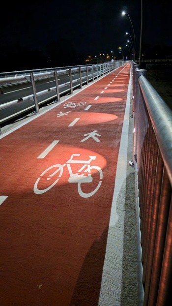 View of a red bicycle and pedestrian path at night illuminated by streetlights with painted symbols in Macerata Marche Italy. View of a red bicycle and pedestrian path at night illuminated by streetlights with painted symbols in Macerata Marche Italy.