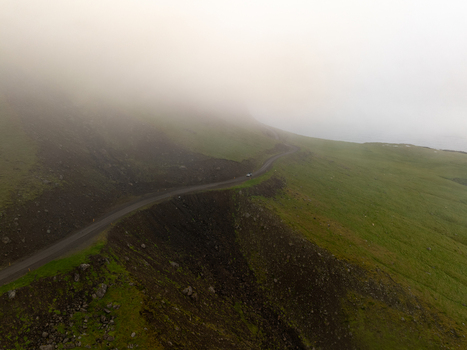 Aerial view of a winding road cutting through the rugged green terrain of the Eastern Region in Iceland. Aerial view of a winding road cutting through the rugged green terrain of the Eastern Region in Iceland.