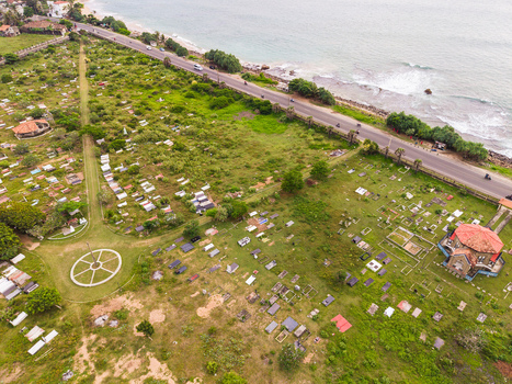 Aerial view of the historic Galle cemetery with headstones and a chapel next to the coastal road with vehicles and ocean waves in Galle Southern Province Sri Lanka. Aerial view of the historic Galle cemetery with headstones and a chapel next to the coastal road with vehicles and ocean waves in Galle Southern Province Sri Lanka.