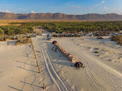 Aerial view of tents lined up in the desert sands contrasting against the distant mountains and lush green vegetation Kadrihnitin Socotra Yemen. Aerial view of tents lined up in the desert sands contrasting against the distant mountains and lush green vegetation Kadrihnitin Socotra Yemen.
