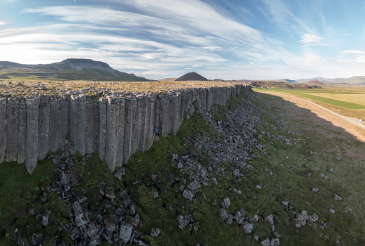 Aerial view of Gerduberg Cliffs featuring basalt columns rocky slopes and green fields under a bright sky in Raudhamelur Eyja og Miklaholtshr Iceland. Aerial view of Gerduberg Cliffs featuring basalt columns rocky slopes and green fields under a bright sky in Raudhamelur Eyja og Miklaholtshr Iceland.