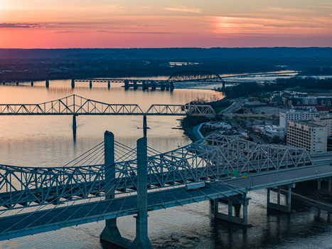 Aerial view of multiple bridges spanning the Ohio River under a vibrant sunset sky with city buildings along the waterfront Louisville Kentucky United States. Aerial view of multiple bridges spanning the Ohio River under a vibrant sunset sky with city buildings along the waterfront Louisville Kentucky United States.