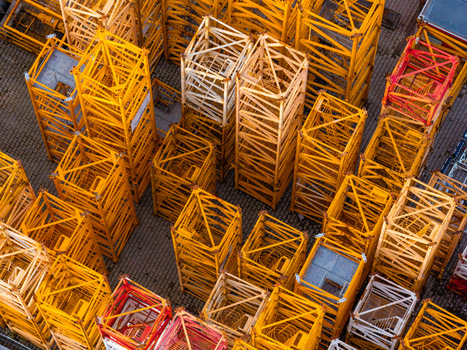 Aerial view of stacked yellow and red tower crane mast sections in a storage yard in Masovian Voivodeship Poland.