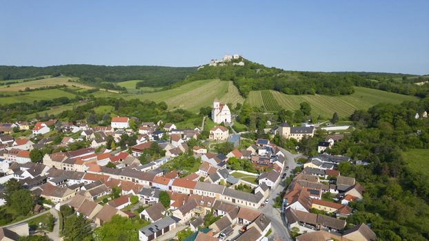 Aerial view of the village nestled amongst rolling green hills with the distinctive white church and castle ruins standing out against the landscape Falkenstein bei Poysdorf Lower Austria Austria. Aerial view of the village nestled amongst rolling green hills with the distinctive white church and castle ruins standing out against the landscape Falkenstein bei Poysdorf Lower Austria Austria.