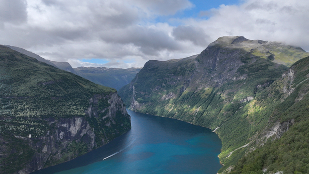 Aerial view of a deep blue fjord winding between steep lush green mountains under a cloudy sky in Nordland Norway. Aerial view of a deep blue fjord winding between steep lush green mountains under a cloudy sky in Nordland Norway.