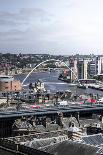 Aerial view of the Gateshead Millennium Bridge spanning the River Tyne with historic buildings and the Tyne Bridge in Newcastle upon Tyne England United Kingdom. Aerial view of the Gateshead Millennium Bridge spanning the River Tyne with historic buildings and the Tyne Bridge in Newcastle upon Tyne England United Kingdom.