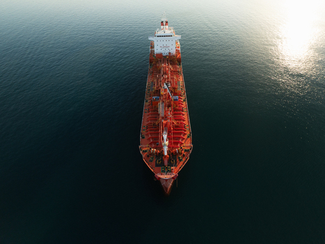 Aerial view of a large red oil tanker ship sailing on the calm blue sea with sunlight reflecting on the water Augusta Sicily Italy. Aerial view of a large red oil tanker ship sailing on the calm blue sea with sunlight reflecting on the water Augusta Sicily Italy.