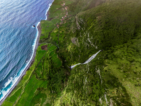 Aerial view of the dramatic coastline where the verdant landscape meets the vast ocean punctuated by cascading waterfalls Faj&atilde; Grande Azores Portugal.