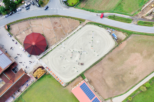 Aerial view of Reitclub In der Point Poxdorf featuring the outdoor riding arena stables and surrounding green fields under bright daylight in Poxdorf Bayern Germany. Aerial view of Reitclub In der Point Poxdorf featuring the outdoor riding arena stables and surrounding green fields under bright daylight in Poxdorf Bayern Germany.