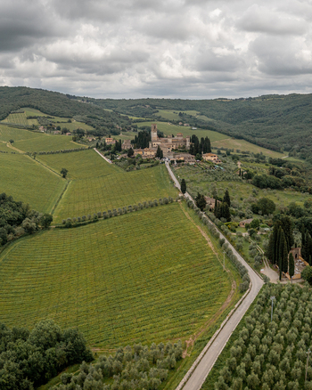 Aerial view of the historic village of Passignano nestled among rolling green vineyards and olive groves under a cloudy sky in Passignano Toscana Italy. Aerial view of the historic village of Passignano nestled among rolling green vineyards and olive groves under a cloudy sky in Passignano Toscana Italy.