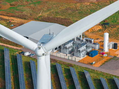 Aerial view of Chelveston Renewable Energy BESS facility featuring a large wind turbine rows of solar panels and battery storage units in Chelveston England United Kingdom. Aerial view of Chelveston Renewable Energy BESS facility featuring a large wind turbine rows of solar panels and battery storage units in Chelveston England United Kingdom.