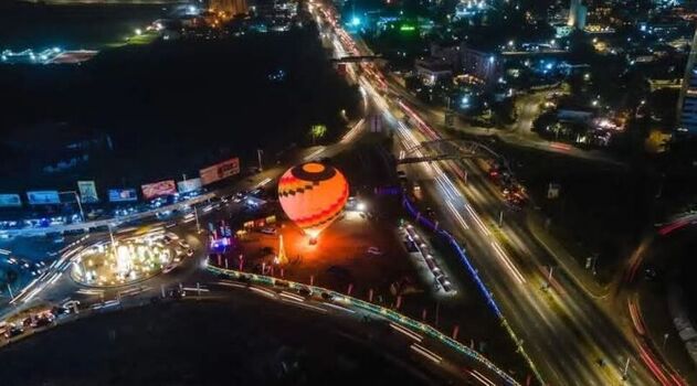 Aerial view of a glowing hot air balloon at night situated near a busy roundabout with light trails from traffic on the highway in Ghana. Aerial view of a glowing hot air balloon at night situated near a busy roundabout with light trails from traffic on the highway in Ghana.
