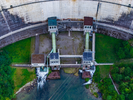 Aerial view of the Barrage de Rossens dam featuring concrete walls water outlet pipes and surrounding greenery in Pont la Ville Fribourg Switzerland.
