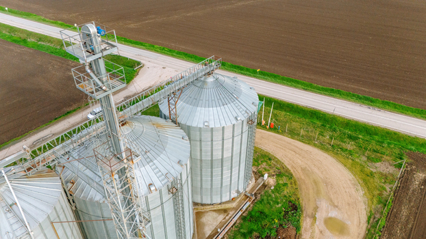 Aerial view of silver silos gleam under the sun contrasting against the dark earth and vibrant green grass Sremska Mitrovica Vojvodina Serbia. Aerial view of silver silos gleam under the sun contrasting against the dark earth and vibrant green grass Sremska Mitrovica Vojvodina Serbia.