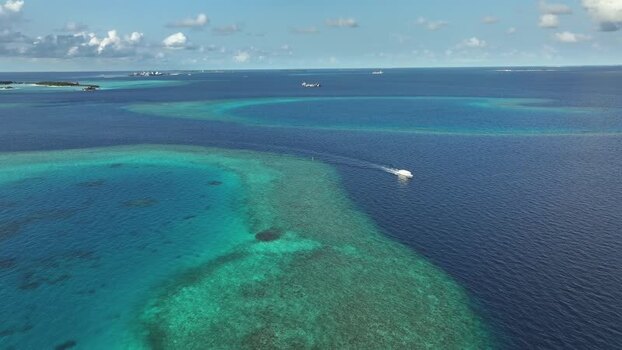 Aerial view of a boat cruising near coral reefs and turquoise waters Maldives. Aerial view of a boat cruising near coral reefs and turquoise waters Maldives.