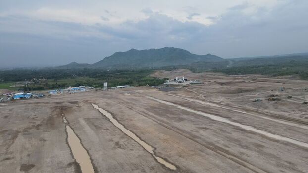 Aerial view of Dhoho International Airport construction site with expansive cleared land muddy terrain and distant mountains under a cloudy sky in Kecamatan Grogol Jawa Timur Indonesia. Aerial view of Dhoho International Airport construction site with expansive cleared land muddy terrain and distant mountains under a cloudy sky in Kecamatan Grogol Jawa Timur Indonesia.
