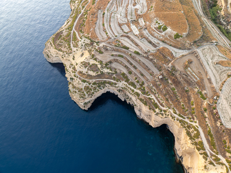 Aerial view of the rugged Sanap Cliffs meeting the deep blue sea a contrast of arid land and endless ocean Munxar Gozo Malta. Aerial view of the rugged Sanap Cliffs meeting the deep blue sea a contrast of arid land and endless ocean Munxar Gozo Malta.