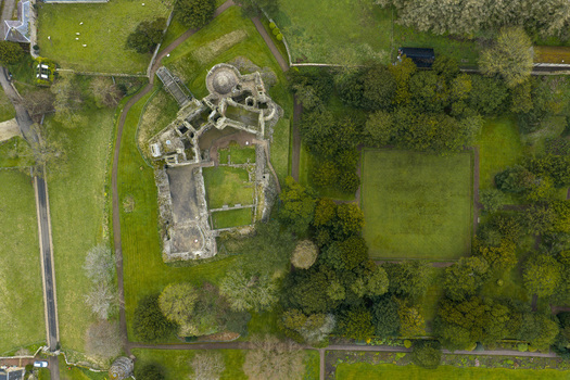Aerial view of the historic stone ruins of Dirleton Castle and Gardens surrounded by manicured lawns and lush green trees in Dirleton Scotland United Kingdom. Aerial view of the historic stone ruins of Dirleton Castle and Gardens surrounded by manicured lawns and lush green trees in Dirleton Scotland United Kingdom.