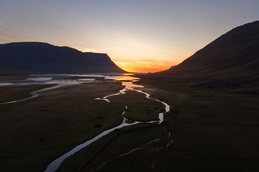 Aerial view of the sunset over the winding river and dramatic mountains in Flateyri Isafjardarbaer Iceland. Aerial view of the sunset over the winding river and dramatic mountains in Flateyri Isafjardarbaer Iceland.