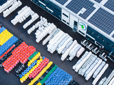 Jelgava Latvia 04 July 2026 Aerial view of a manufacturing facility with rows of colorful polymer pipes and white wrapped pallets featuring solar panels on the industrial roof.