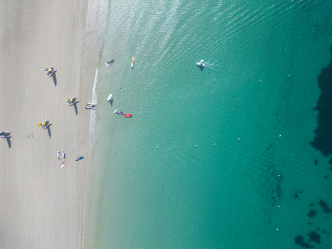 Aerial view of windsurfers and small sailboats on the white sandy beach and turquoise waters of the coast in Trebeurden Brittany France. Aerial view of windsurfers and small sailboats on the white sandy beach and turquoise waters of the coast in Trebeurden Brittany France.