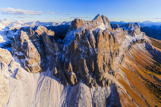 Aerial view of Torri del Vajolet and Catinaccio peaks rise in stark contrast against the serene blue sky kissed by the warm glow of the sun Trentino South Tyrol Italy.