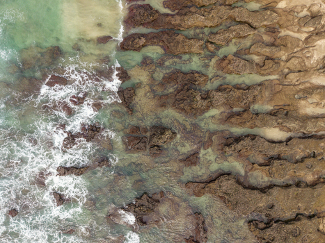 Aerial view of the rocky shoreline at Hartenbos with waves crashing against jagged rocks and clear turquoise water in Mossel Bay Western Cape South Africa. Aerial view of the rocky shoreline at Hartenbos with waves crashing against jagged rocks and clear turquoise water in Mossel Bay Western Cape South Africa.
