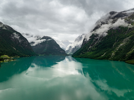 Aerial view of the turquoise waters of Loen fjord surrounded by steep cloud covered mountains in Loen Vestland Norway. Aerial view of the turquoise waters of Loen fjord surrounded by steep cloud covered mountains in Loen Vestland Norway.
