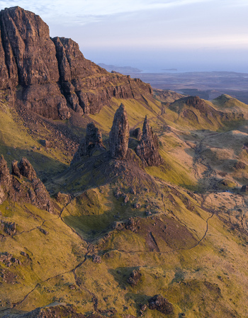 Aerial view of The Storr rock formation with its iconic pinnacles and rugged grassy slopes under soft light on the Isle of Skye Scotland United Kingdom. Aerial view of The Storr rock formation with its iconic pinnacles and rugged grassy slopes under soft light on the Isle of Skye Scotland United Kingdom.