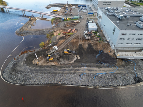 Oulu North Ostrobothnia Finland 18 September 2026 Aerial view of construction site at waterfront with heavy machinery excavators and trucks working near the riverbank. Oulu North Ostrobothnia Finland 18 September 2026 Aerial view of construction site at waterfront with heavy machinery excavators and trucks working near the riverbank.