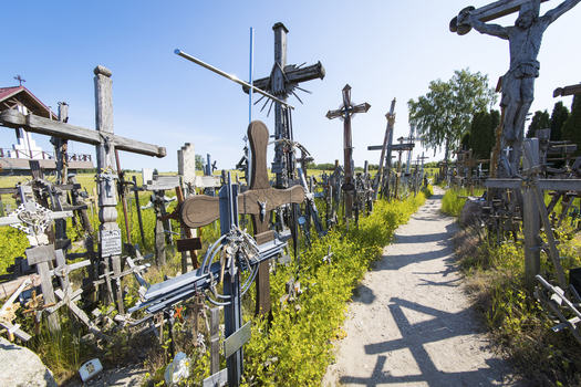 View of the Hill of Crosses with numerous wooden and metal crucifixes along a dirt path under a clear blue sky Siauliai Siauliu apskritis Lithuania. View of the Hill of Crosses with numerous wooden and metal crucifixes along a dirt path under a clear blue sky Siauliai Siauliu apskritis Lithuania.