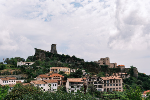 View of the historic Kruje Castle and Skanderbeg Museum on a hillside with traditional red tiled rooftops under a cloudy sky in Kruje Durres County Albania.