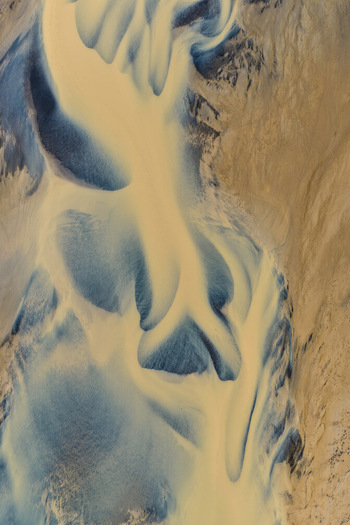 Aerial view of the braided glacial river patterns flowing from Drangajokull glacier showcasing intricate sediment channels and blue glacial water in Isafjordur Isafjardarbaer Iceland. Aerial view of the braided glacial river patterns flowing from Drangajokull glacier showcasing intricate sediment channels and blue glacial water in Isafjordur Isafjardarbaer Iceland.