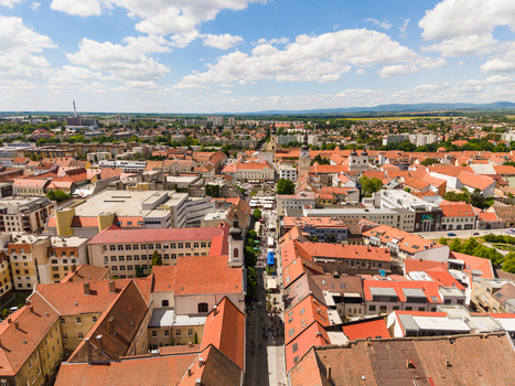 Aerial view of the historic city center featuring red tiled rooftops a bustling pedestrian street and church towers under a cloudy blue sky in Trnava Trnava Region Slovakia. Aerial view of the historic city center featuring red tiled rooftops a bustling pedestrian street and church towers under a cloudy blue sky in Trnava Trnava Region Slovakia.
