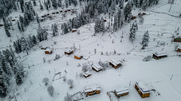 Aerial view of snow laden cabins nestled amidst a forest of evergreens a serene winter scene in the valley Sharda Azad Kashmir Pakistan. Aerial view of snow laden cabins nestled amidst a forest of evergreens a serene winter scene in the valley Sharda Azad Kashmir Pakistan.