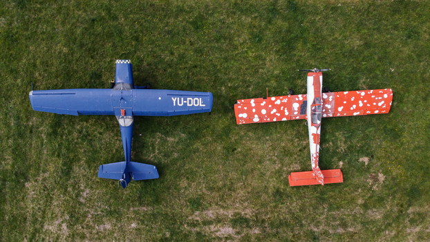 Serbia 11 April 2021 Aerial view of two small light aircraft parked on a grassy field one blue and one red with white spots. Serbia 11 April 2021 Aerial view of two small light aircraft parked on a grassy field one blue and one red with white spots.