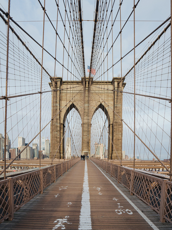 View of the Brooklyn Bridge with its iconic stone arches steel cables and wooden pedestrian walkway featuring the Manhattan skyline in the background New York New York United States.