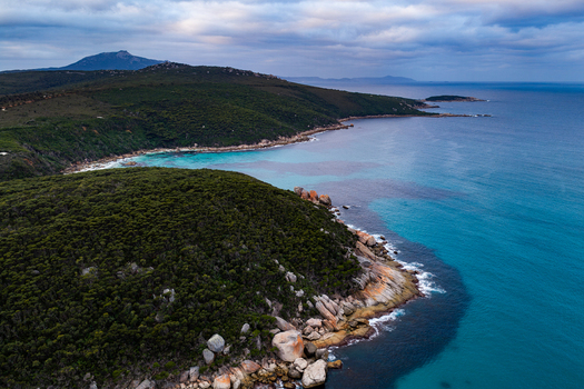Aerial view of Bettys Beach featuring rugged granite boulders turquoise ocean waters and dense coastal vegetation in Albany WA Australia. Aerial view of Bettys Beach featuring rugged granite boulders turquoise ocean waters and dense coastal vegetation in Albany WA Australia.