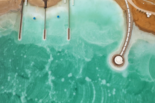 Aerial view of the turquoise waters meeting the sandy shore near the structured docks and circular platform Ein Bokek Israel. Aerial view of the turquoise waters meeting the sandy shore near the structured docks and circular platform Ein Bokek Israel.