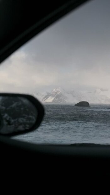 View of snowy mountains and a dark ocean Norway.