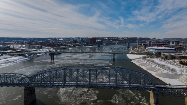 Aerial view of the Taylor Southgate Bridge crossing the icy Ohio River with snow covered banks and the city skyline under a blue sky in Cincinnati Ohio United States. Aerial view of the Taylor Southgate Bridge crossing the icy Ohio River with snow covered banks and the city skyline under a blue sky in Cincinnati Ohio United States.